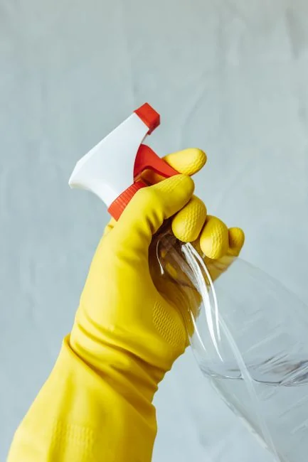 services-04 Anonymous male wearing yellow latex gloves and dark t shirt wiping mirror in bathroom with paper napkin